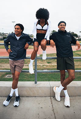 Three people posing on a metal railing with a grassy field and trees in the background.